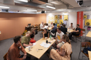 Participants seated around tables in a workshop space, discussing ideas in small groups during a business event